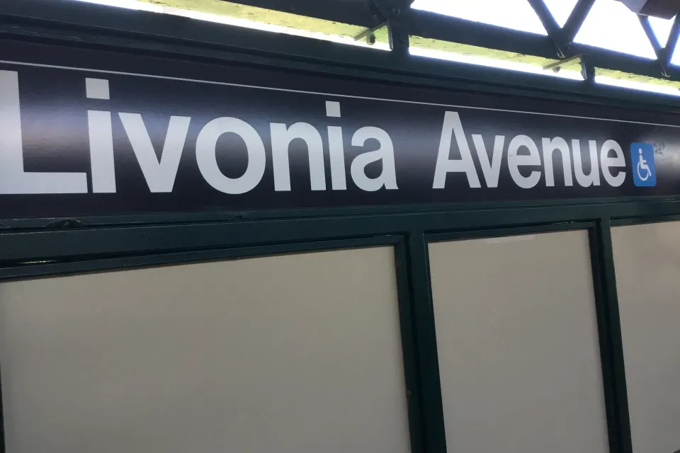 Close-up of black and white Livonia Avenue subway sign with blue accessibility symbol